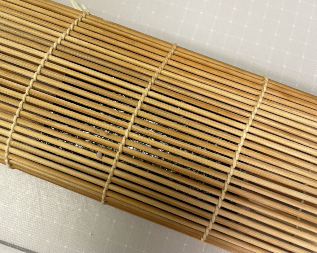 ポーク玉子おにぎりのまきすで巻くところ